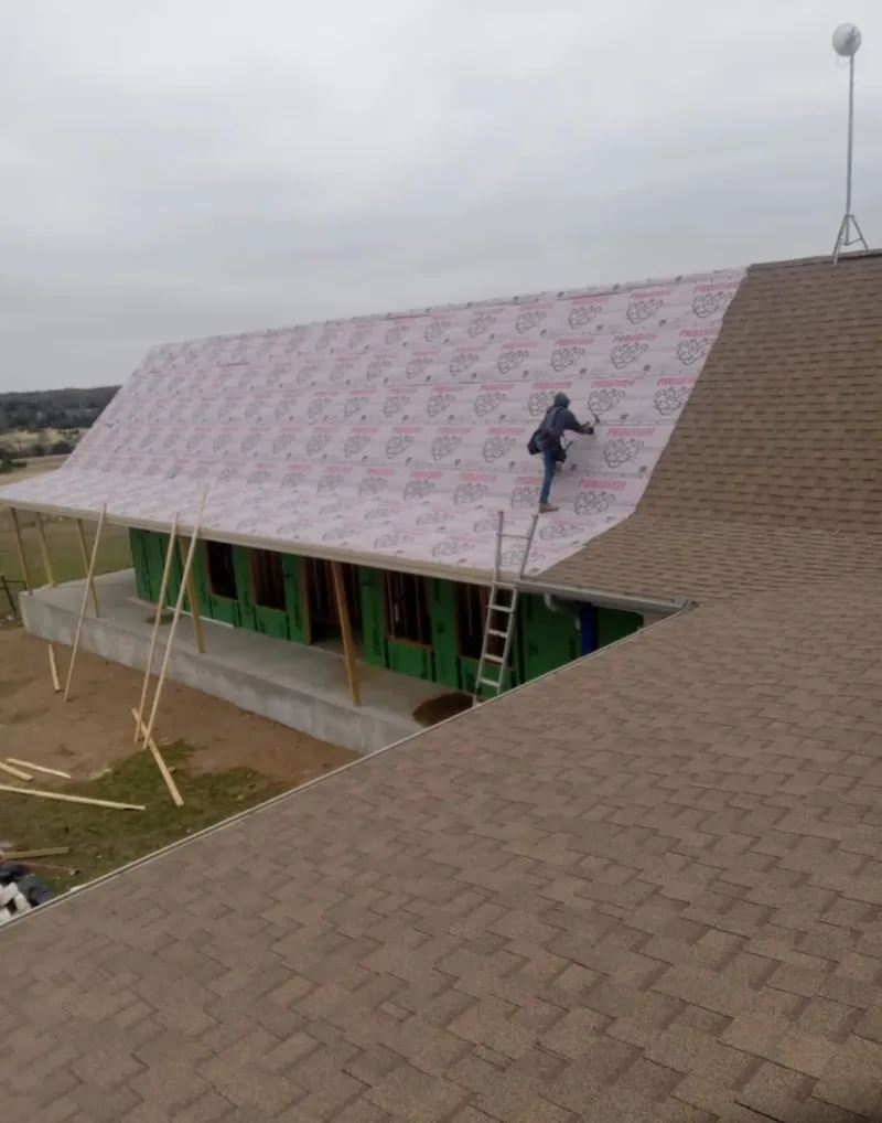 Worker preparing underlayment for a metal roof installation in Notre Dame